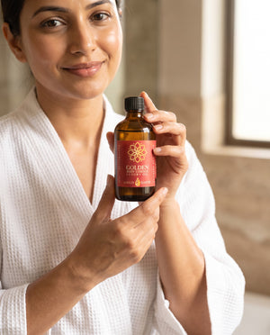 Woman applying Golden Body Essence to softly radiant skin
